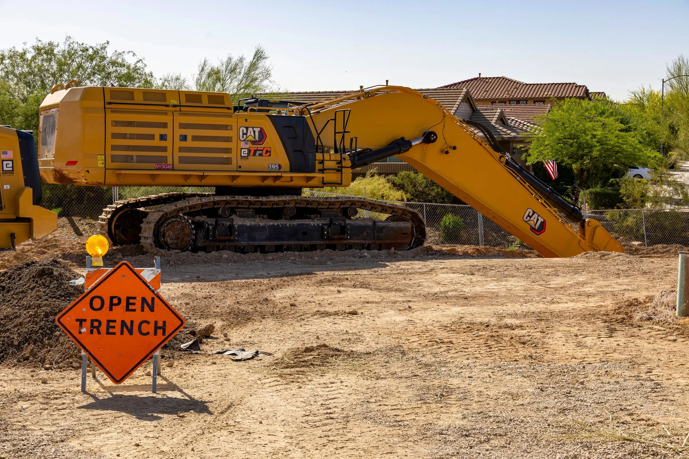 Excavator beside an orange Open Trench sign